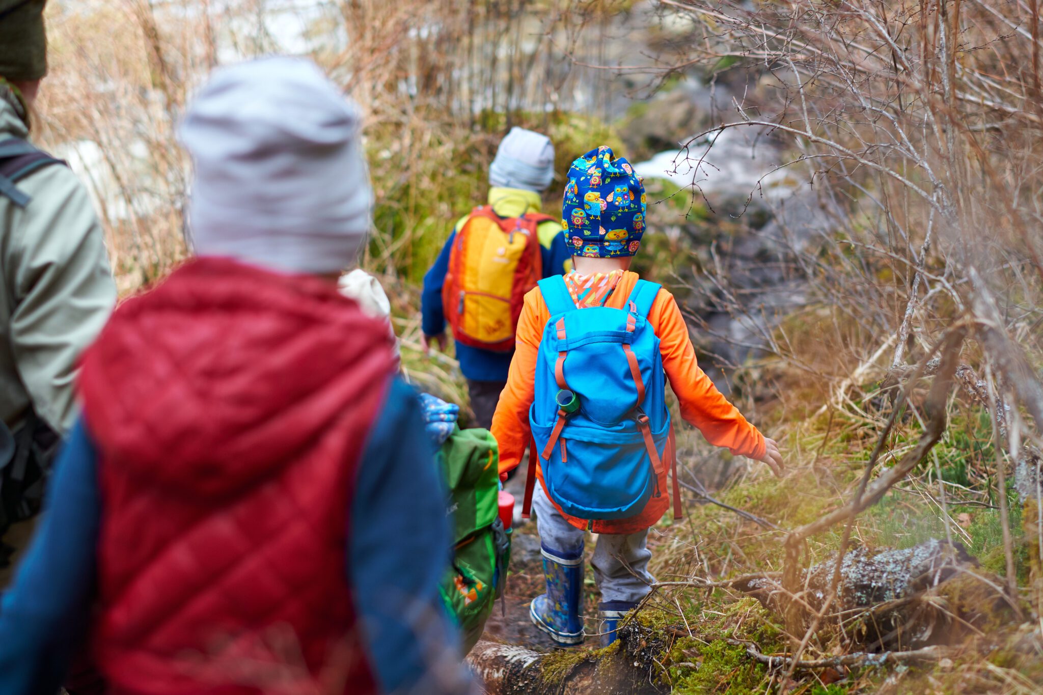 group of children with backpacks walking along mountain path