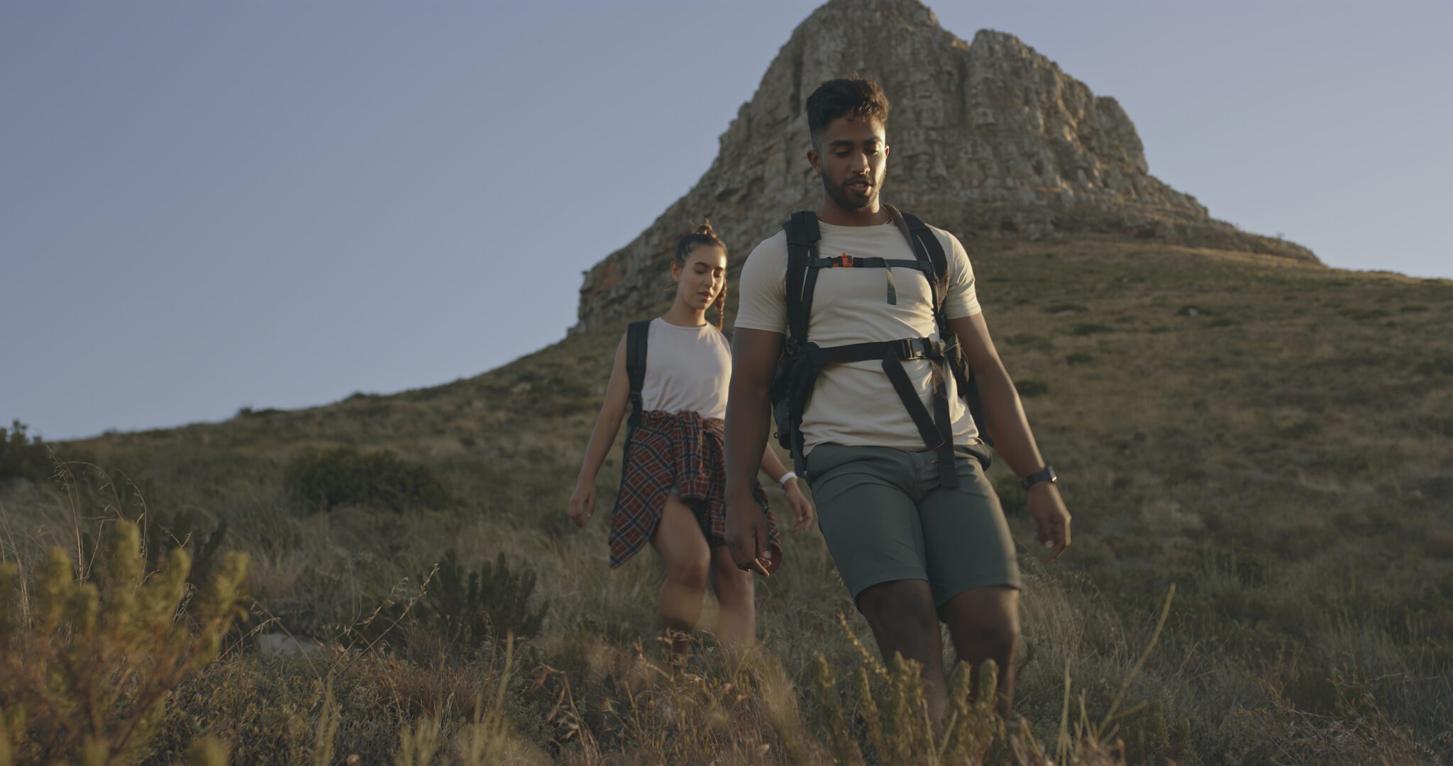 A couple hiking up a mountain on a travel adventure. A happy young man and woman in love walking through nature